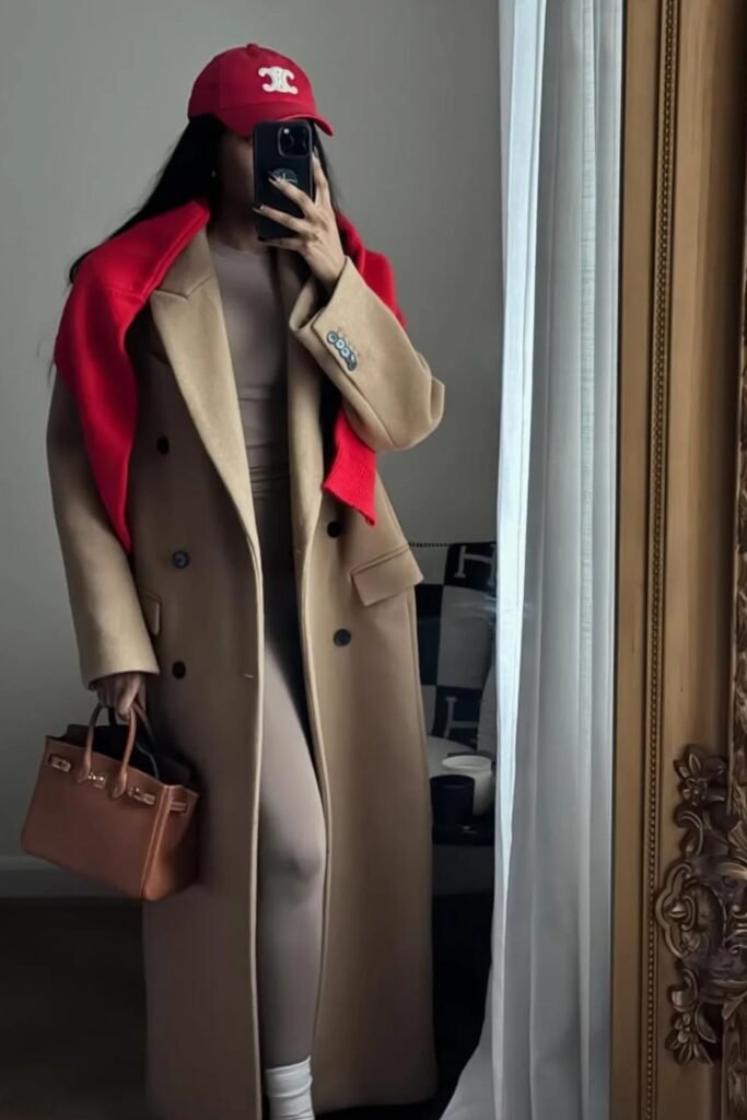 Beige Bodysuit + Long Camel Coat + Red Sweater Draped Over Shoulders + Red Cap + Brown Structured Bag