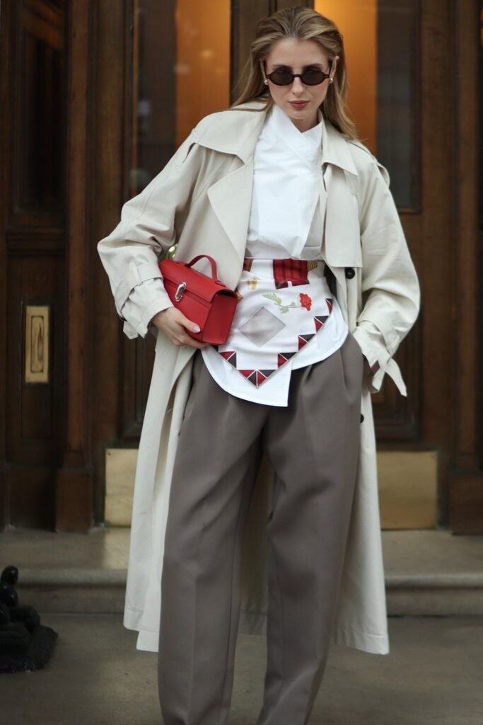 Beige Trench Coat + White Draped Shirt + Grey Wide-Leg Trousers + Printed Scarf Belt + Red Mini Bag