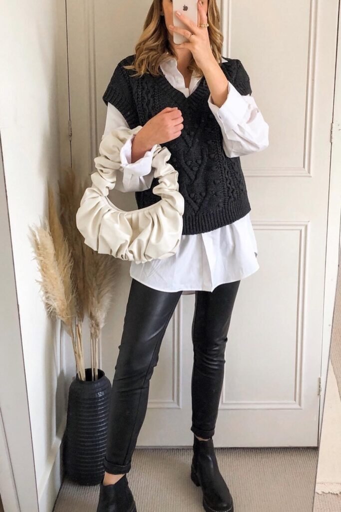 Black Cable-Knit Sweater Vest + Oversized White Shirt + Black Faux-Leather Leggings + Black Chelsea Boots + Scrunched Shoulder Bag