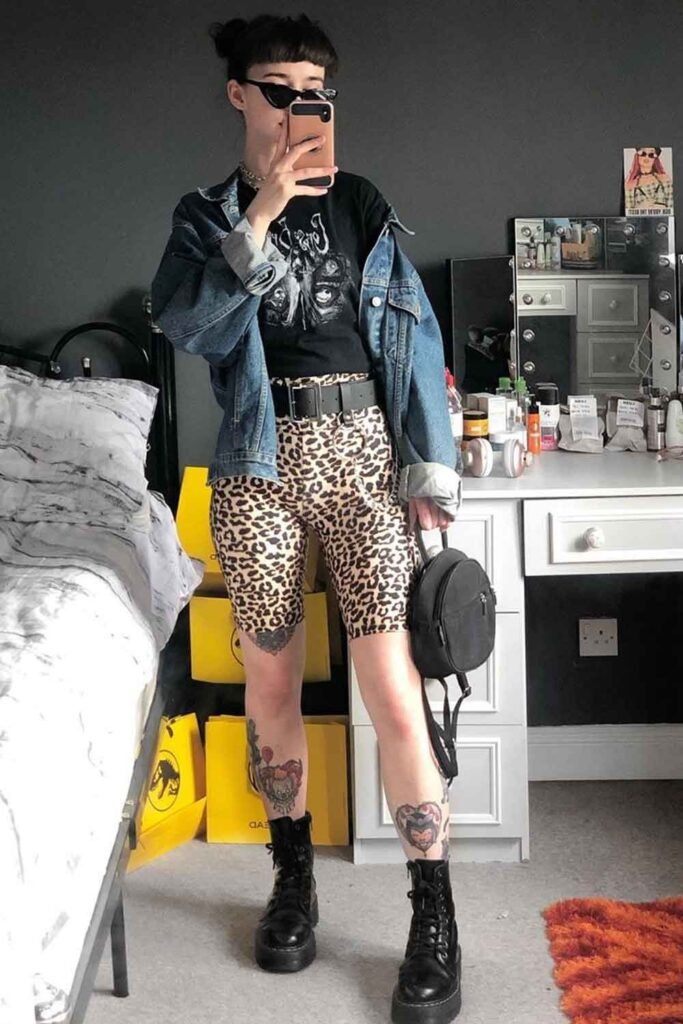 Black Graphic T-shirt + Leopard Print Biker Shorts + Oversized Denim Jacket + Combat Boots + Mini Backpack