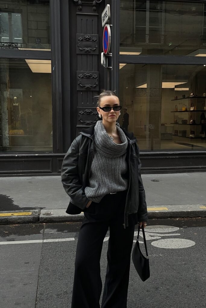 Black Leather Jacket + Grey Chunky Cowl-Neck Sweater + Black Wide-Leg Trousers + Black Mini Shoulder Bag + Black Slim Sunglasses