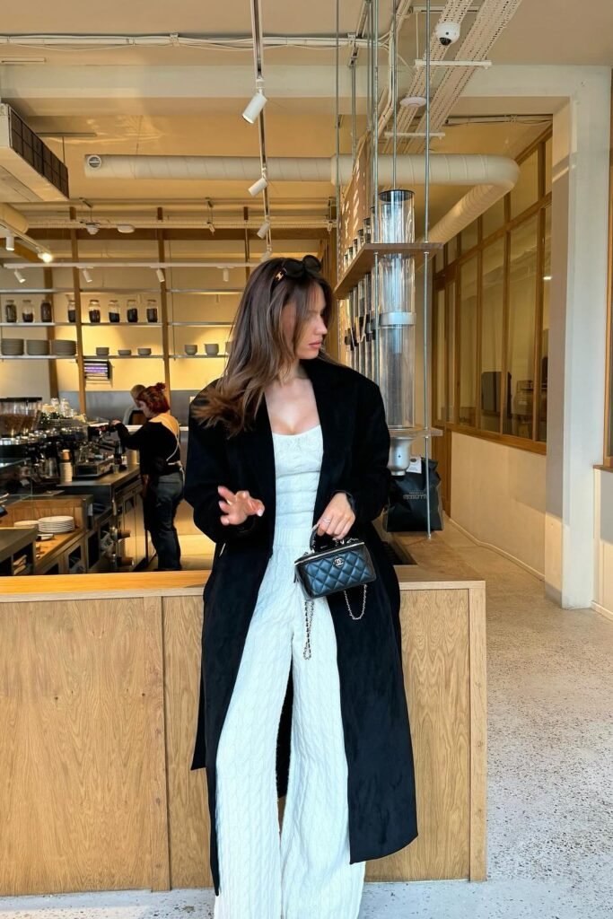 Black Longline Coat + White Knit Jumpsuit + Quilted Chanel Mini Bag