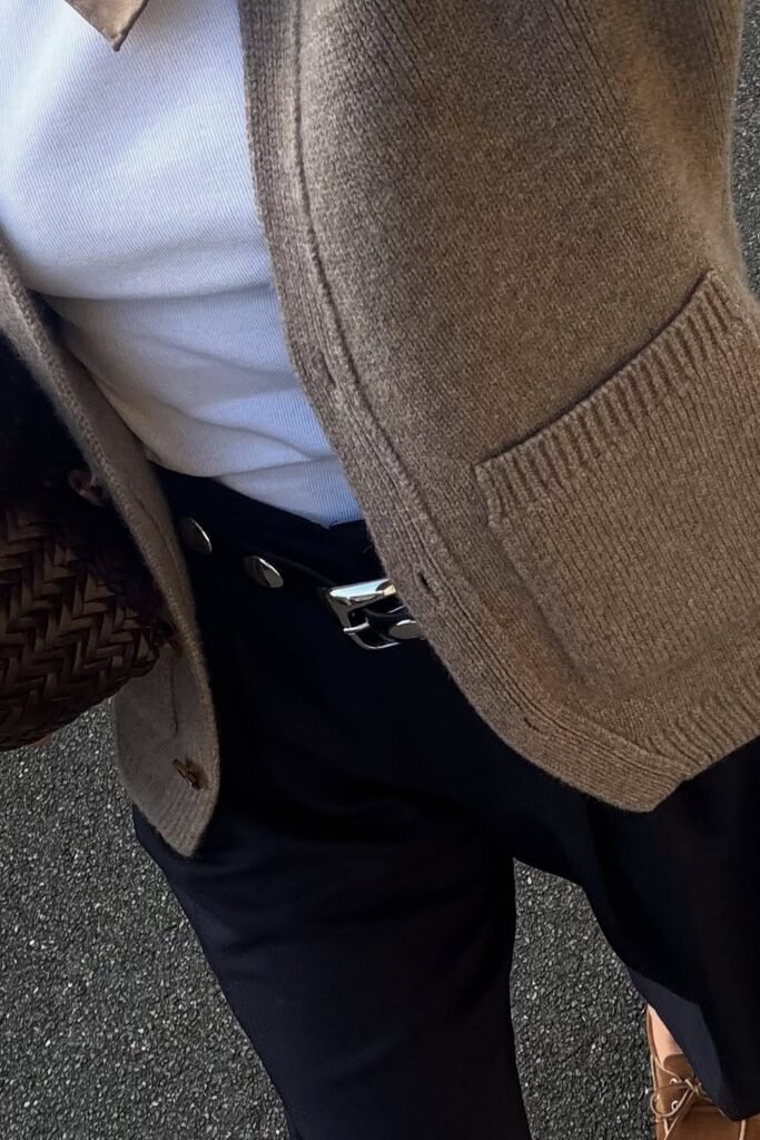 Brown Knit Cardigan + White Ribbed Tank Top + Black High-Waisted Trousers + Black Belt with Silver Buckle + Brown Woven Bag + Brown Loafers