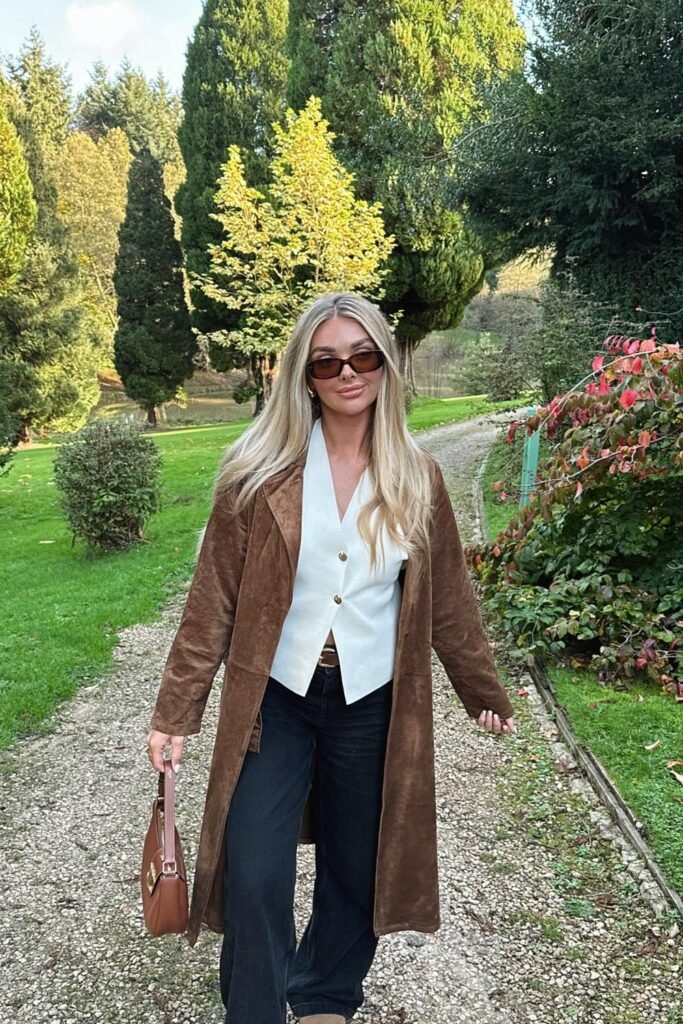 Brown Suede Coat + White Button Vest + Black Wide-Leg Jeans + Brown Shoulder Bag + Sunglasses