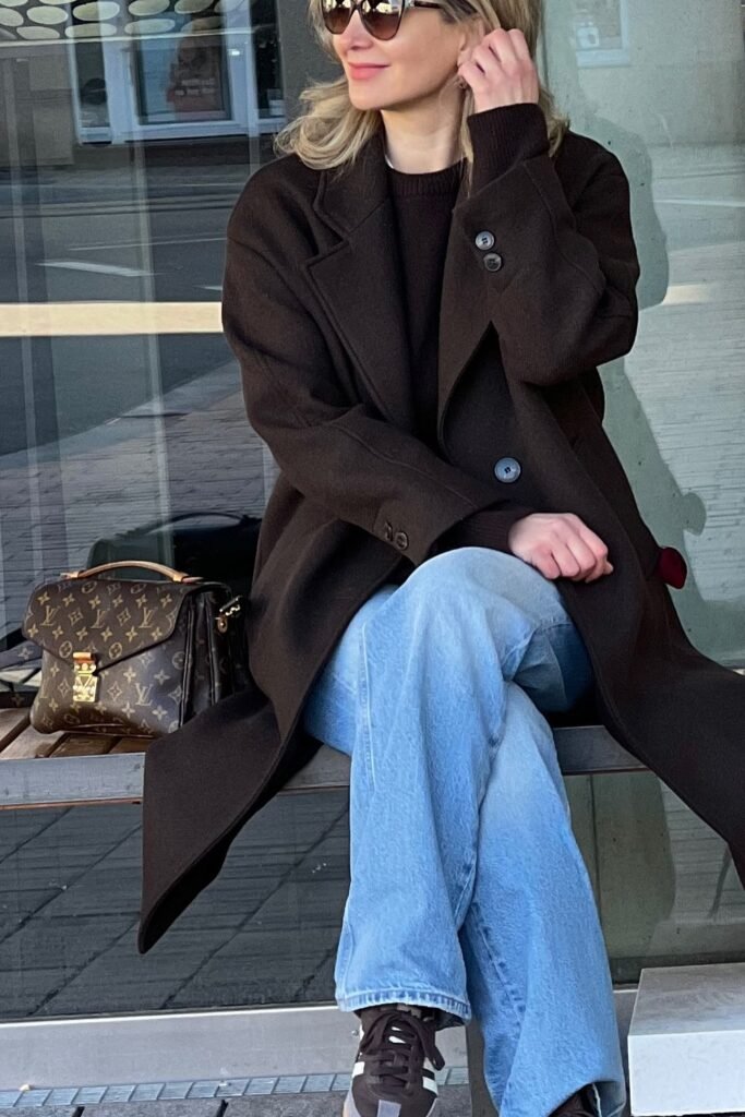 Brown Sweater + Long Brown Coat + Light Blue Wide-Leg Jeans + Brown Sneakers + Brown Monogram Handbag
