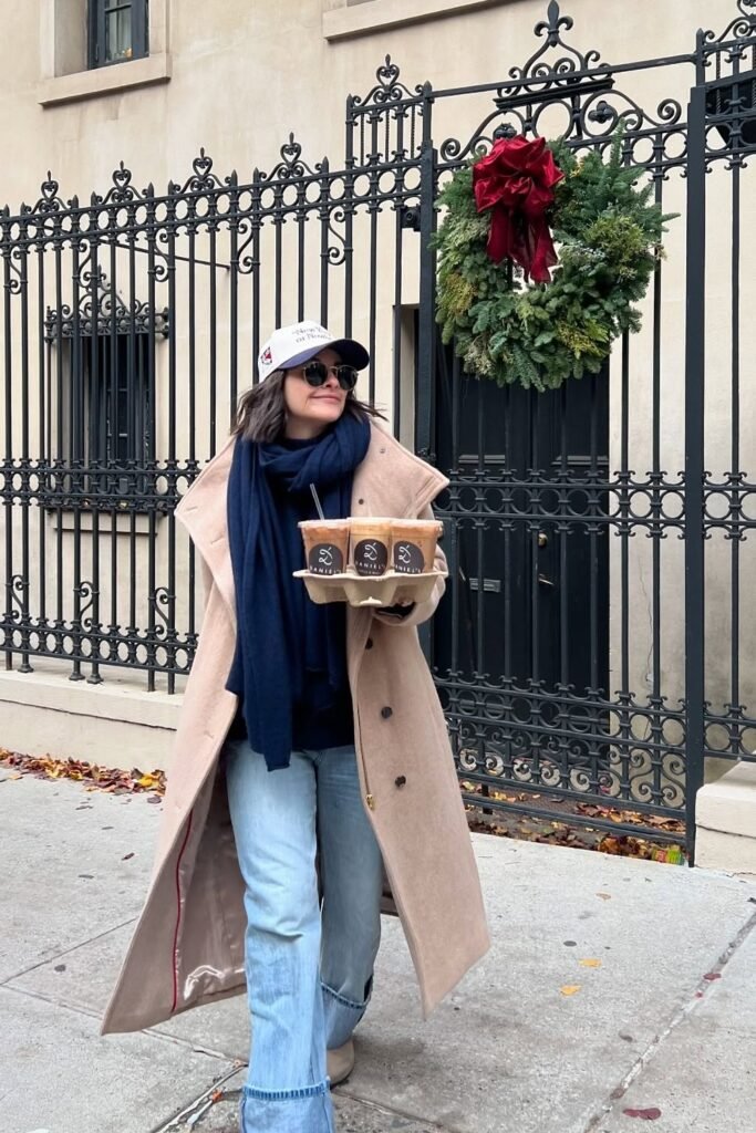 Camel Long Coat + Navy Scarf + Light-Wash Flared Jeans + Beige Boots + Baseball Cap + Sunglasses