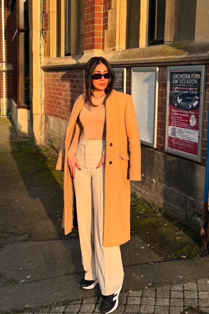 Camel Long Coat + Nude Fitted Knit + Cream Wide-Leg Trousers + Black-and-White Sneakers + Sunglasses