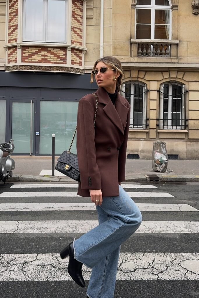 Chocolate Brown Double-Breasted Blazer + Black Turtleneck + Light Wash Straight-Leg Jeans + Black Heeled Boots + Black Quilted Chanel Flap Bag + Gold Hoop Earrings