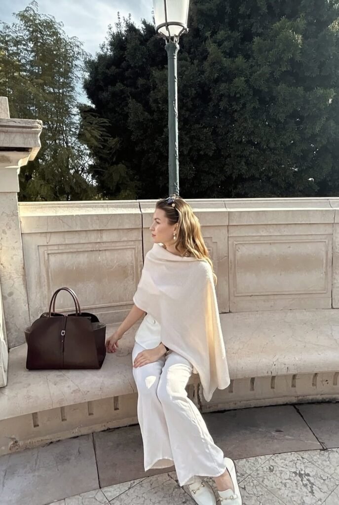Cream Cashmere Poncho + White Wide-Leg Trousers + White Loafers + Pearl Hair Clip + Dark Brown Weekender Bag