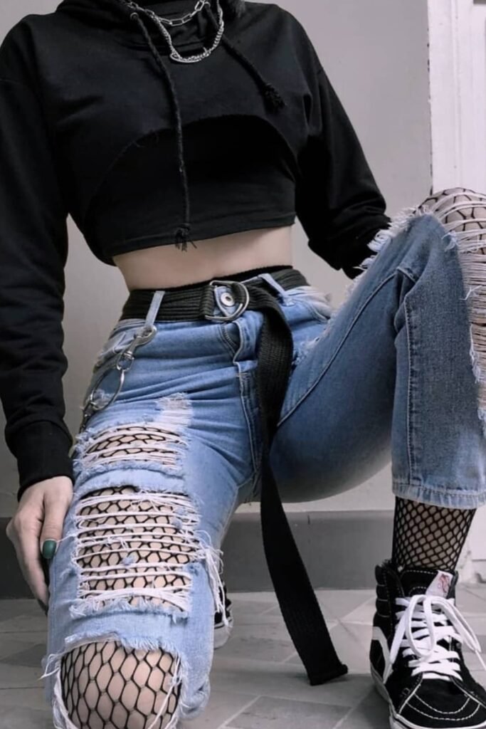 Cropped Black Hoodie + Ripped Light-Wash Jeans with Fishnet Layer Underneath + Black Belt with Ring Detail + Black Vans Sk8-Hi Sneakers