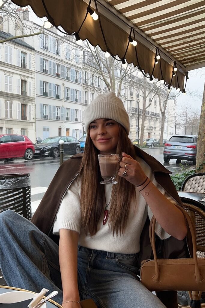 Dark Brown Coat Draped + White Short-Sleeve Sweater + Blue Jeans + White Beanie + Suede Tan Handbag