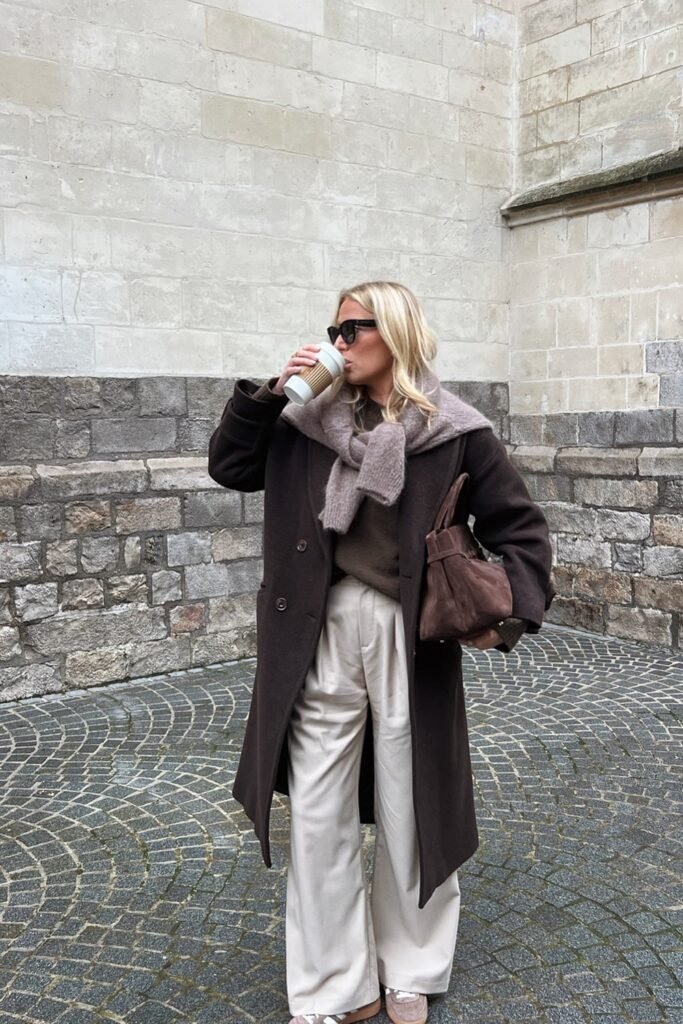 Dark Brown Oversized Coat + Brown Knit Sweater + Cream Wide-Leg Trousers + Taupe Scarf + Brown Suede Bag