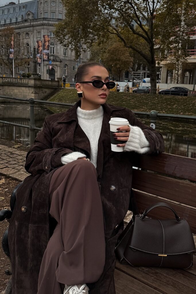 Dark Brown Suede Trench Coat + White Knit Sweater + Brown Wide-Leg Trousers + White Sneakers + Brown Structured Bag