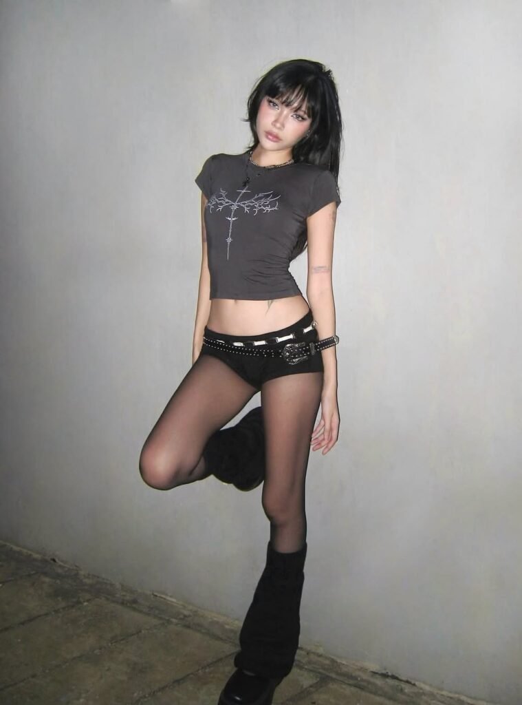 Fitted Black Graphic Crop Top + Black Mini Shorts with Studded Belt + Sheer Black Tights + Black Furry Leg Warmers + Black Boots