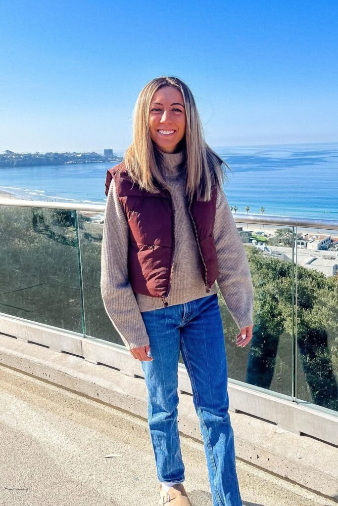 Maroon Puffer Vest + Grey Knit Sweater + Blue Straight Jeans + Beige Slip-On Shoes