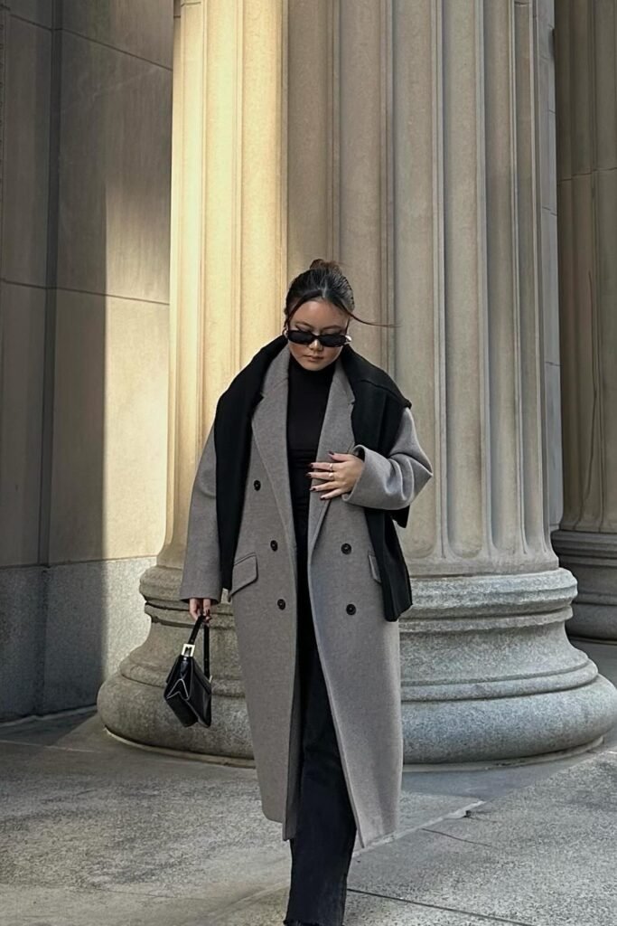 Grey Long Coat + Black Top + Black Trousers + Black Knit Sweater Draped Over Shoulders + Black Mini Handbag + Sunglasses