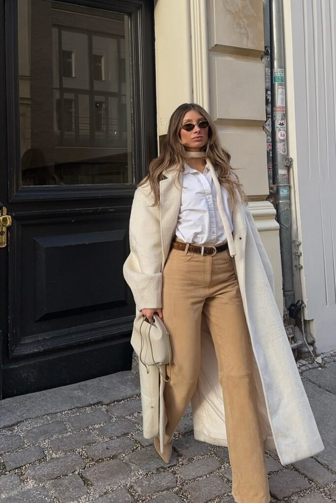 Ivory Longline Coat + White Button-Up Shirt + Camel High-Waist Wide-Leg Pants + Brown Belt + White Structured Mini Bag + Oval Sunglasses