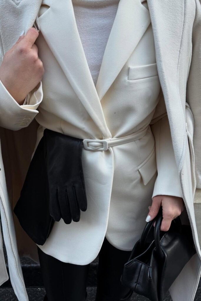 Ivory Overcoat + Ivory Belted Blazer + Cream Knit + Black Leather Leggings + Black Mini Handbag + Black Leather Gloves