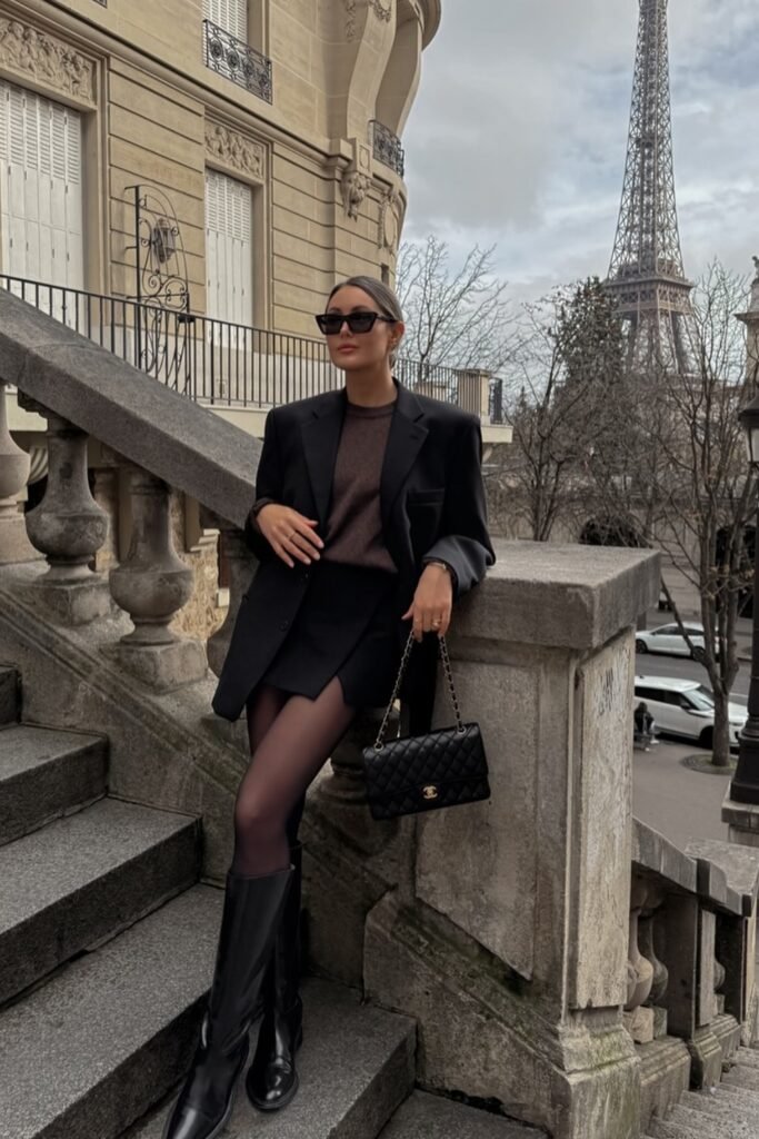Oversized Black Blazer + Brown Knit Sweater + Mini Skirt + Sheer Tights + Black Knee-High Boots + Quilted Chanel Bag