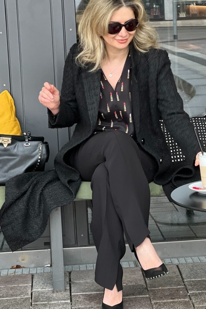 Printed Black Blouse + Long Black Textured Coat + Black Slim Pants + Black Studded Flats + Black Structured Bag