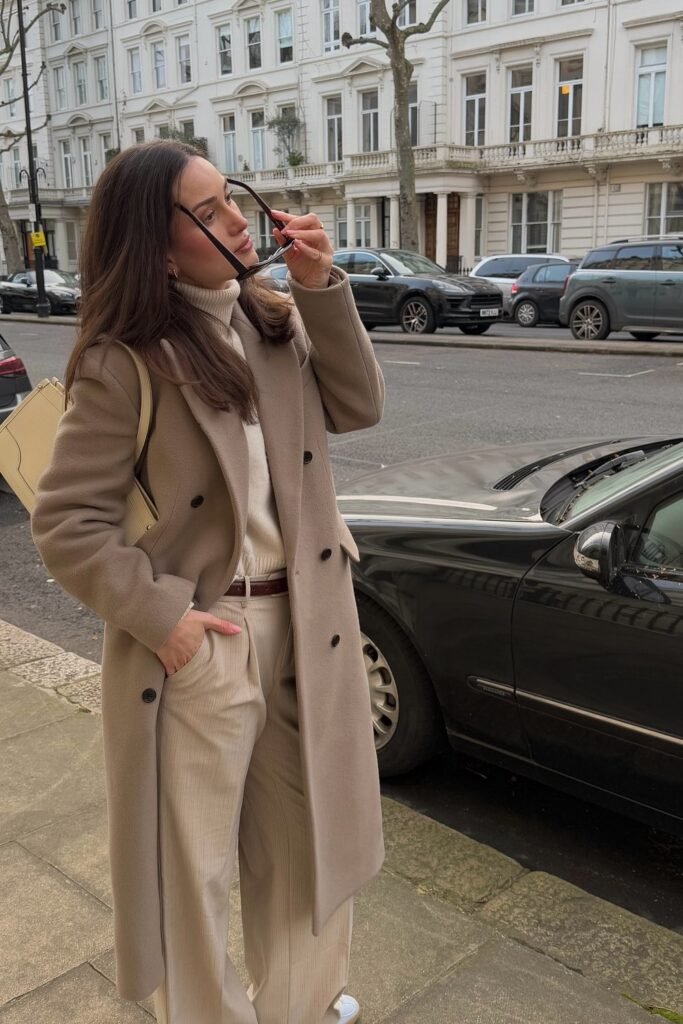 Taupe Double-Breasted Wool Coat + Cream Turtleneck + Beige Wide-Leg Trousers + Brown Belt + Cream Shoulder Bag
