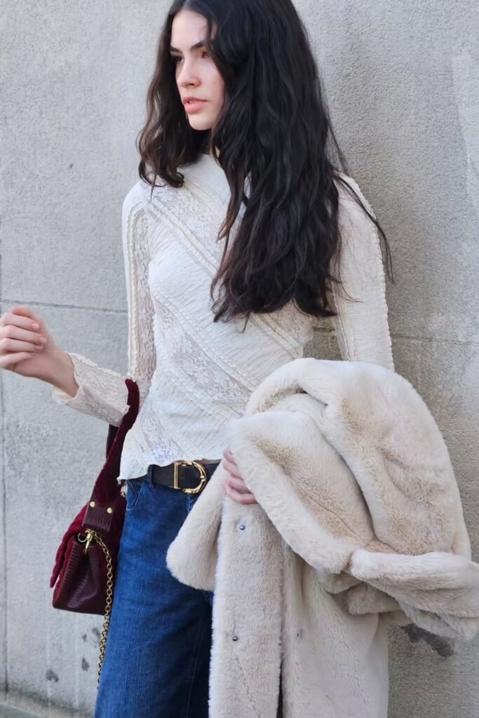 White Lace Long-Sleeve Top + Blue Jeans + Black Belt with Gold Buckle + Cream Faux Fur Coat + Burgundy Shoulder Bag