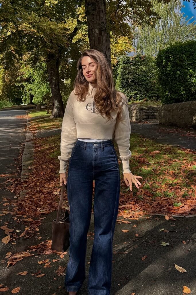 Beige Cropped Logo Sweatshirt + Dark Wash Flared Jeans + Dark Brown Tote Bag