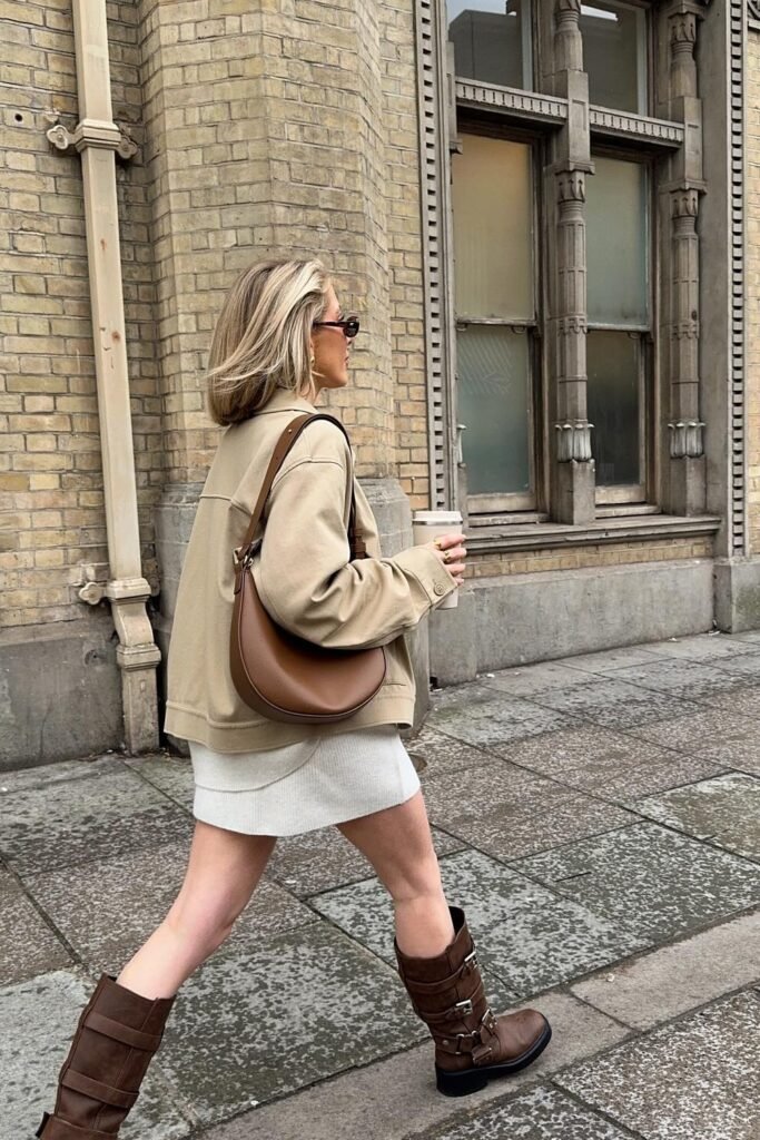 Beige Jacket + Cream Mini Skirt/Dress + Brown Crescent Bag + Brown Buckled Knee-High Boots