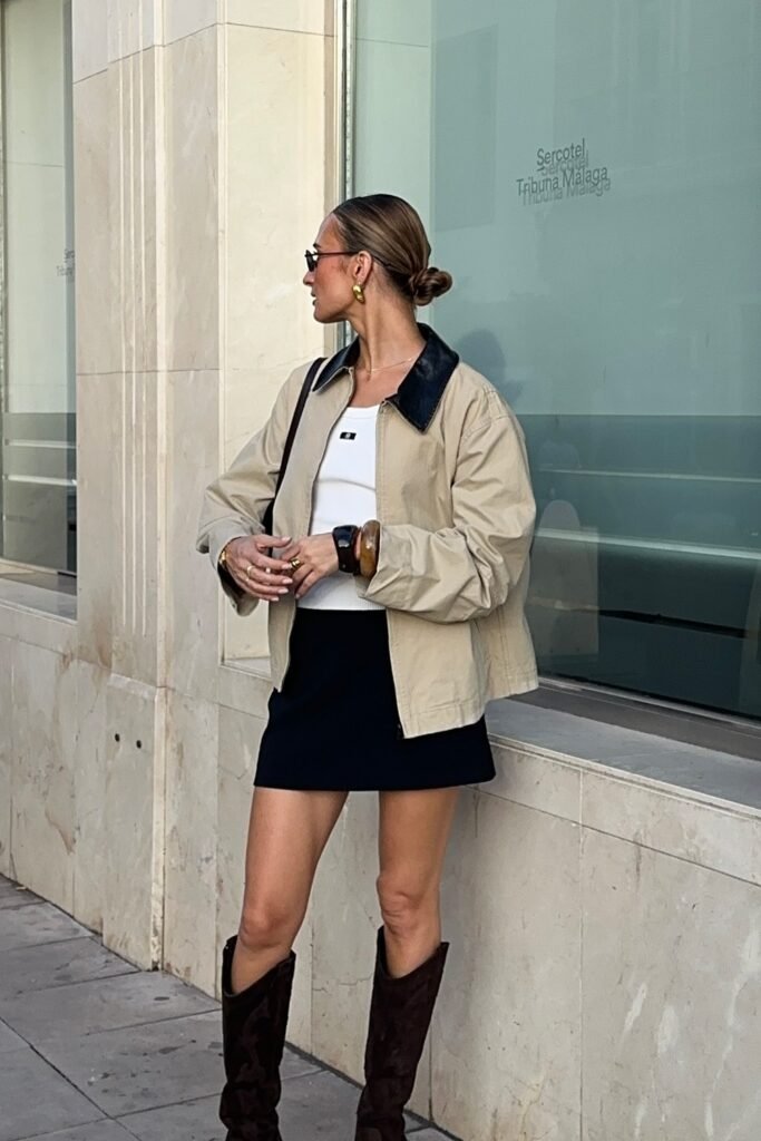 Beige Jacket with Black Collar + White Tank Top + Black Mini Skirt + Brown Suede Knee-High Boots + Gold Accessories