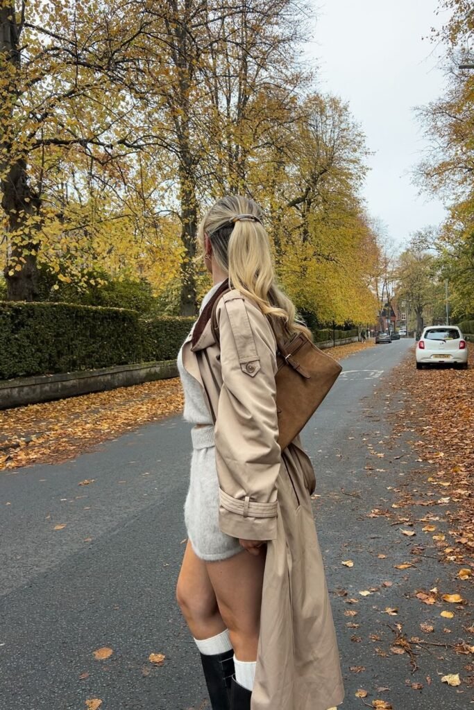 Beige Trench Coat + Light Gray Knit Mock Neck Top + Matching Knit Shorts/Skirt + White Knee-High Socks + Black Tall Boots