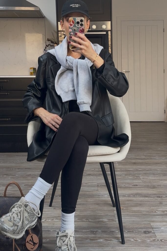 Black Faux Leather Blazer + Grey Sweatshirt (Draped) + Black Top + Black Leggings + Black Cap + White/Grey Sneakers