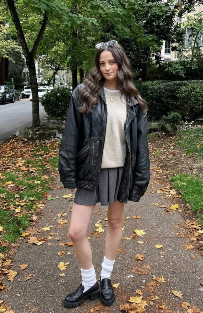 Black Leather Jacket + Cream Knit Sweater + Grey Pleated Skirt + White Knee-High Socks + Chunky Black Loafers