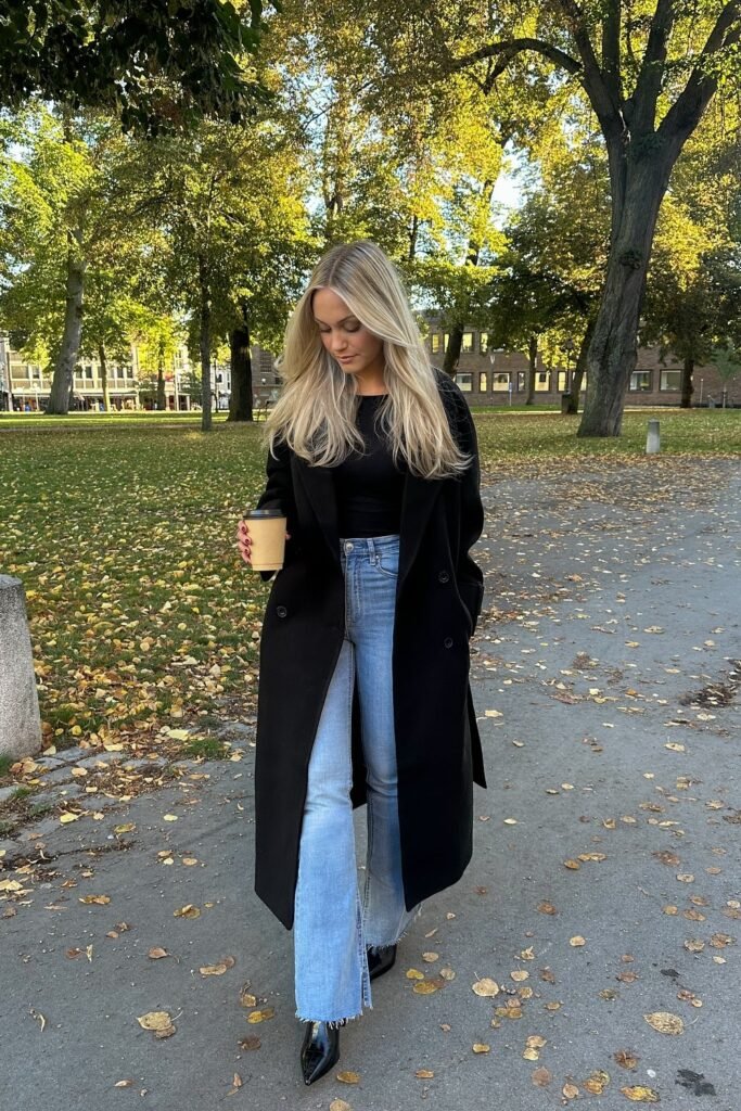 Black Long Coat + Black Top + Light Blue Flared Jeans + Black Pointed Boots + Coffee Cup