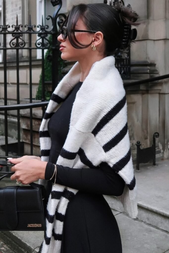 Black Long-Sleeve Midi Dress + Black and White Striped Knit Scarf/Sweater Draped Across Shoulders + Black Mini Top-Handle Bag