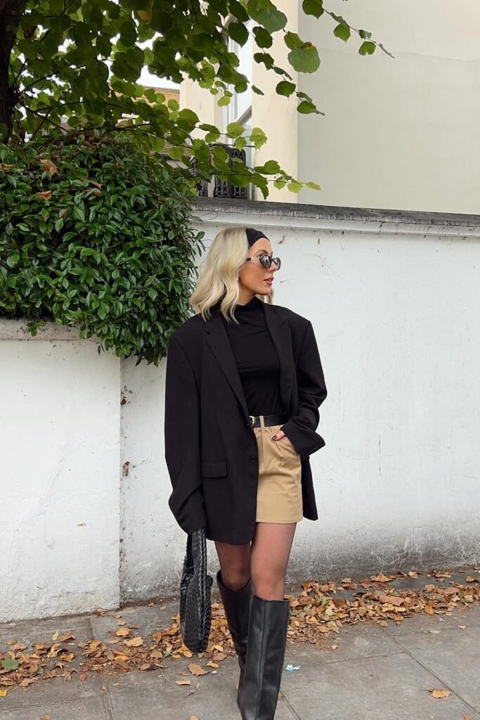 Black Oversized Blazer + Black Turtleneck + Khaki/Tan Mini Skirt + Black Knee-High Boots + Black Woven Handbag
