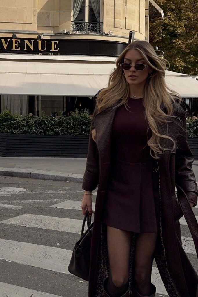 Brown Croc-Effect Leather Coat + Burgundy Bodysuit/Top + Burgundy Pleated Mini Skirt + Black Tights + Black Top-Handle Bag