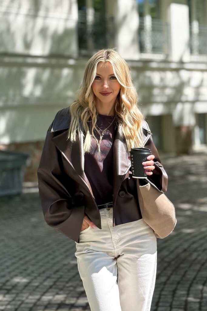 Brown Cropped Faux-Leather Jacket + Dark Graphic T-Shirt + Cream Trousers + Beige Suede Bag