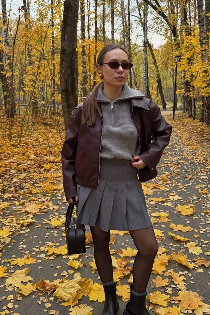 Brown Faux Leather Bomber Jacket + Grey Quarter-Zip Knit Sweater + Grey Pleated Mini Skirt + Black Tights + Black Chelsea Boots