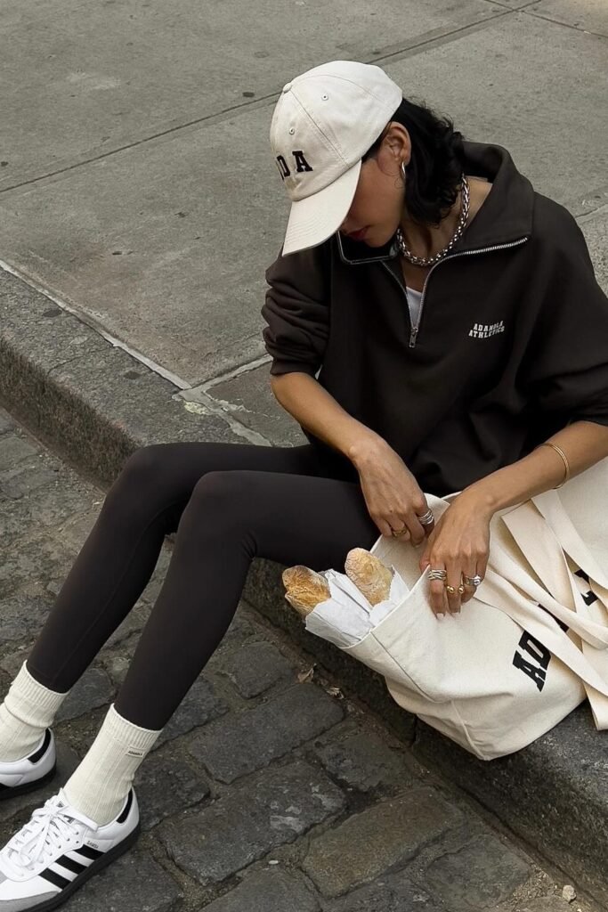 Brown Half-Zip Sweatshirt + Dark Brown Leggings + White Socks + Black and White Sneakers + Cream Baseball Cap