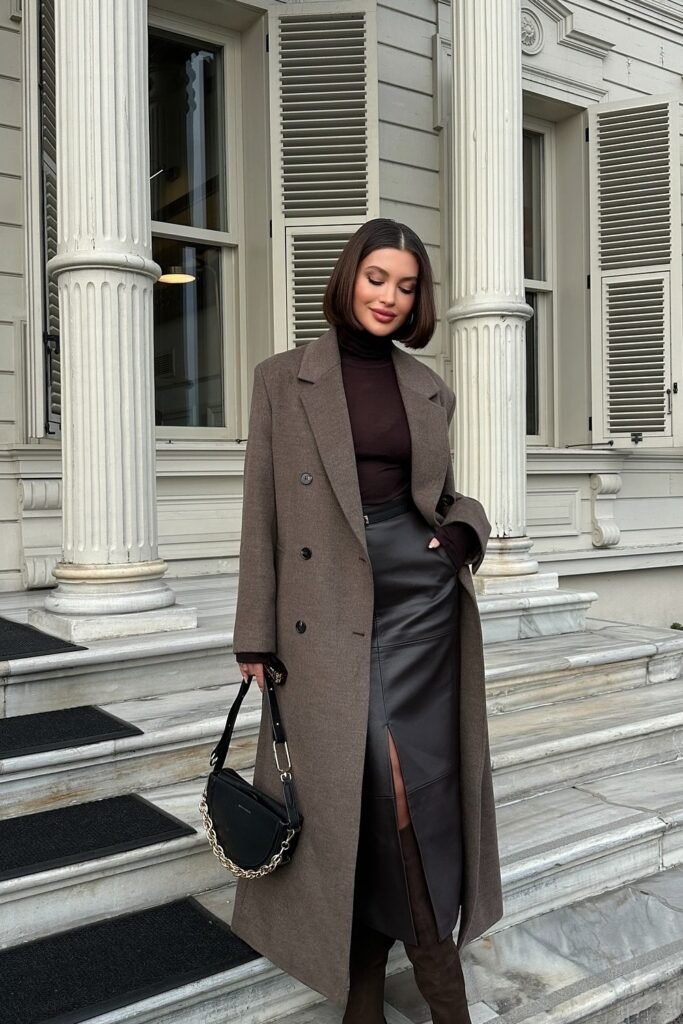 Brown Oversized Coat + Black Turtleneck Top + Leather Midi Skirt with Slit + Knee-High Boots + Black Shoulder Bag with Chain