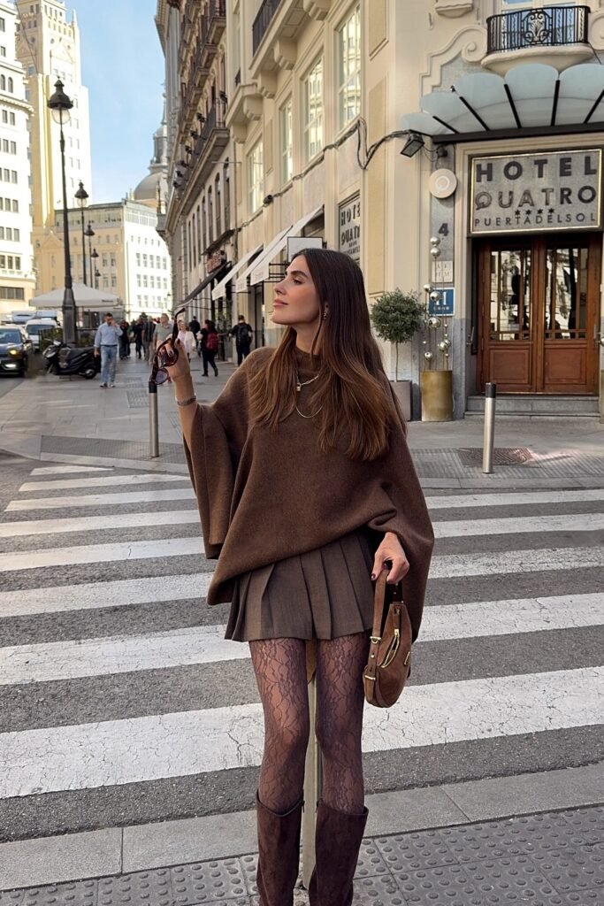 Brown Oversized Poncho Sweater + Brown Pleated Mini Skirt + Patterned Tights + Suede Knee-High Boots