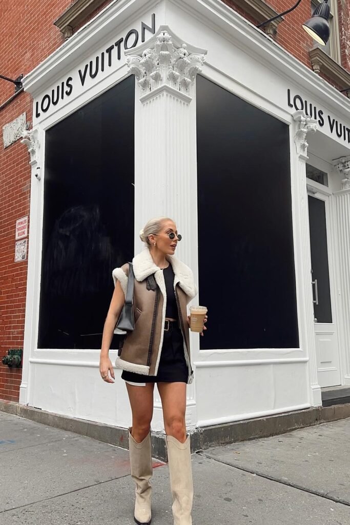 Brown and Cream Shearling Vest + Black T-Shirt + Black Shorts + Black Belt + Cream/Beige Cowboy Boots