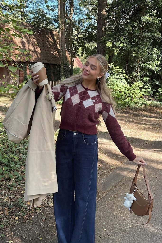 Burgundy Argyle Cropped Cardigan + Dark Wash Wide-Leg Jeans + Carrying a Beige Trench Coat