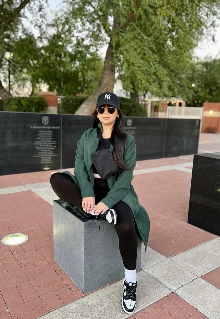 Green Long Coat + Black Crop Top + Black Leggings + Black and White Sneakers + Black Cap + Black Crossbody Bag