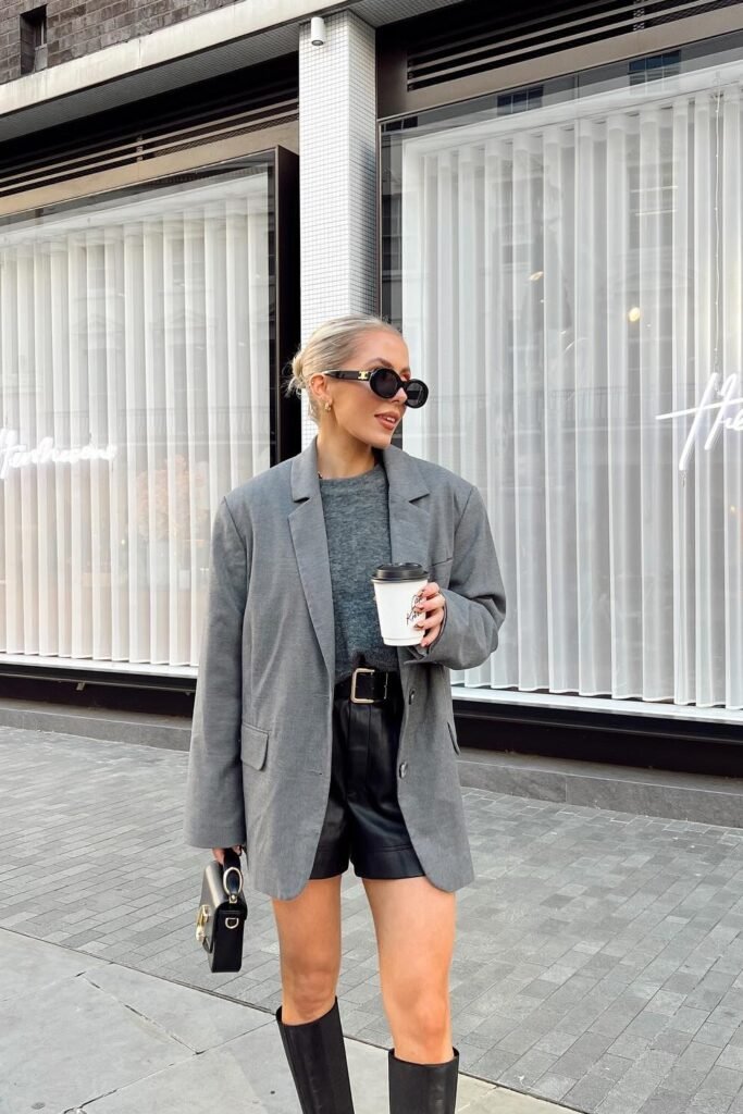 Grey Oversized Blazer + Grey T-Shirt/Sweater + Black Leather Shorts + Black Belt + Black Knee-High Boots
