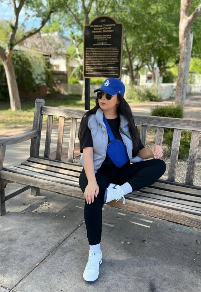 Grey Puffer Vest + Black T-Shirt + Black Leggings + White Sneakers + Blue Cap + Blue Crossbody Bag