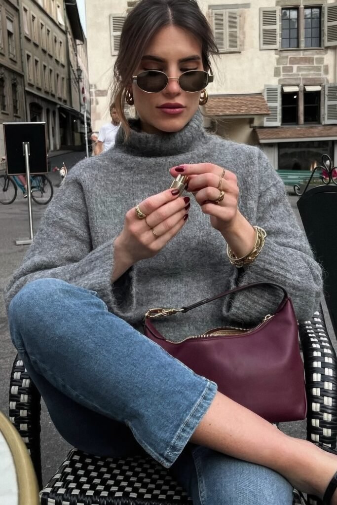 Grey Turtleneck Sweater + Cropped Blue Jeans + Burgundy Shoulder Bag + Gold Jewelry + Oval Sunglasses