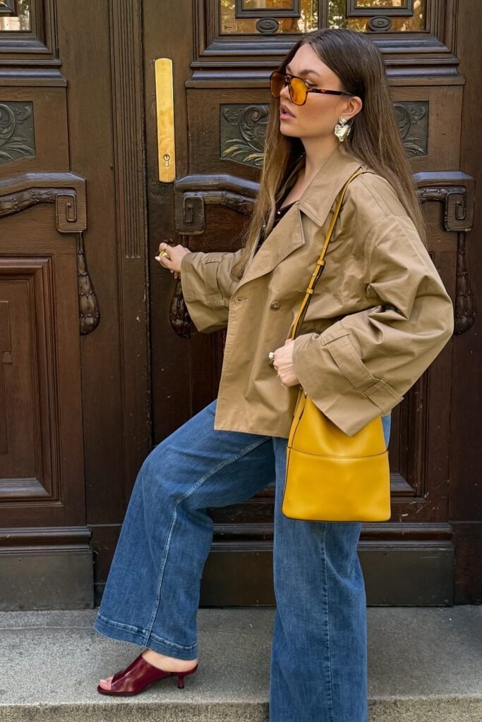 Khaki Cropped Trench Jacket + Black Top + Wide-Leg Jeans + Yellow Bucket Bag + Burgundy Mules