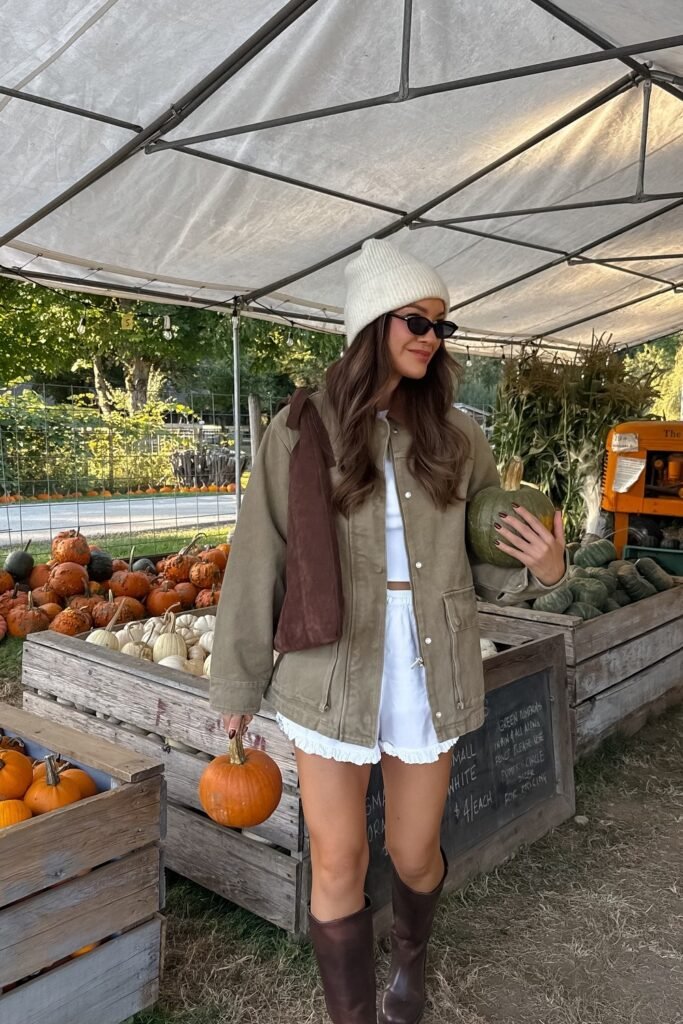 Khaki Utility Jacket + White Ruffled Shorts + White Beanie + Brown Knee-High Boots + Brown Shoulder Bag