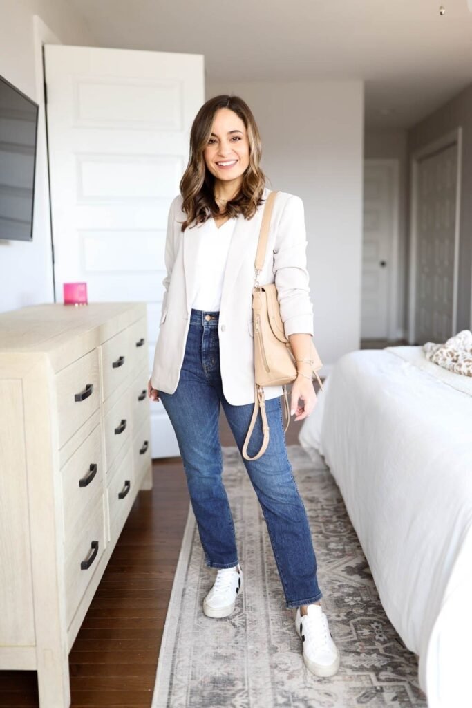 Light Beige Blazer + White V-Neck T-Shirt + Dark Wash Straight Leg Jeans + White and Black Sneakers + Beige Shoulder Bag